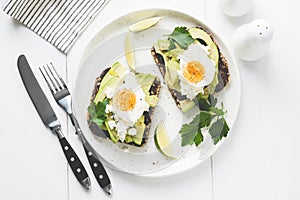 Avocado and egg on whole grain toast on white plate