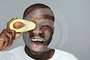 Avocado Facial Treatment. Skin Care With Natural Vitamins. Male African Model Holds Fresh Fruit Near Face.