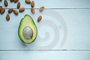 Avocado fruit cutted in half with almond nuts at rustic white wooden background