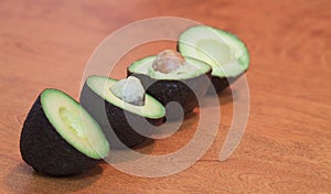 Avocado fruits halved, lined up, wooden background