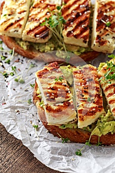 Avocado and grilled haloumi cheese toast with nigella and sesame seeds on crumpled paper. healthy breakfast