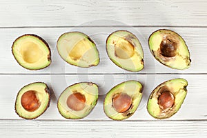 Avocado halves arranged from ripe to over ripen on white boards desk, view from above