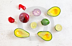 Avocado halves, limes and onions - basic guacamole ingredients on white working board, flat lay photo