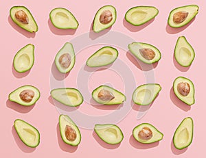 Avocado halves on pink background, flat lay