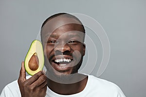 Avocado For Health. Facial Skincare Treatment With Natural Vitamins. Male African Model Holds Fresh Fruit.