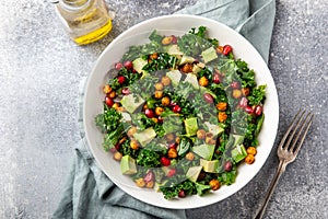 Avocado, kale, roasted chickpeas, almond and pomegranate salad in white bowl