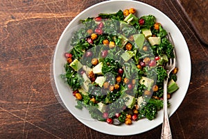 Avocado, kale, roasted chickpeas, almond and pomegranate salad in white bowl