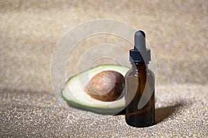 Avocado oil. Essential oil in glass bottle on shiny gold background. Avocado for healthy skin and hair. Cosmetics