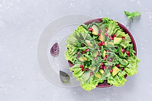 Avocado and pomegranate salad in a clay plate on a gray background. Healthy food. Top view