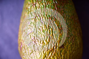 Avocado with relief peel on the purple background