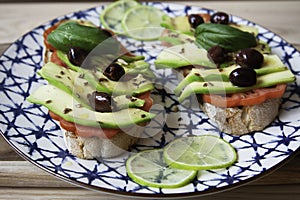 Avocado sandwich toast on ceramic vintage dish. Fresh vegetarian ingredients used on brunch meal. Bruschetta, Avocado, Tomatoes,