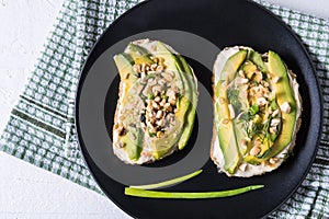 Avocado sandwiches with nuts and cream cheese on a plate, over napkin background. Healthy food for lunch or breakfast. Copy space