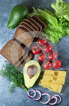 Avocado, sandwiches on whole grain bread with tri-colored tomatoes on rustic baking tray