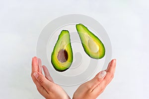 avocado slices fly into women`s hands on white background