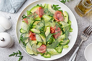 Avocado, smoked salmon and cucumber salad on white plate