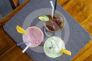 Avocado smoothie, watermelon shake and cold tea in a glass on a wooden table. Tropical drink concept . Top view, closeup