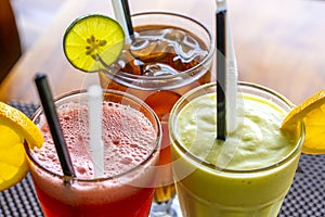 Avocado smoothie, watermelon shake and cold tea in a glass on a wooden table. Tropical drink concept . Top view, closeup