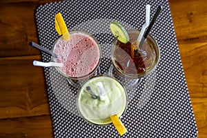 Avocado smoothie, watermelon shake and cold tea in a glass on a wooden table. Tropical drink concept . Top view, closeup