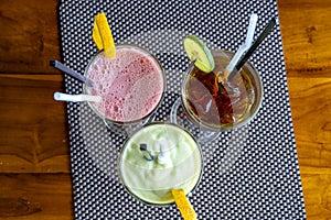 Avocado smoothie, watermelon shake and cold tea in a glass on a wooden table. Tropical drink concept . Top view, closeup