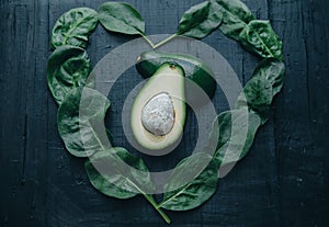 Avocado and spinach in the form of heart on black board background. Diet/healthy/detox food concept. Space for text