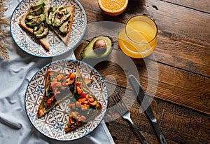 Avocado and spinach toasts with red bell pepper, fresh squeezed orange juice on dark wooden board. Vegetarian food, healthy diet