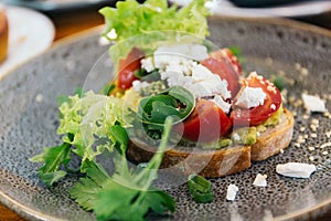 Avocado Toast with Cherry Tomatoes and Feta Cheese. Roast, eating.