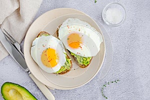 Avocado toast with fried egg and sea salt on a plate on a grey background. A healthy breakfast or lunch. Horizontal orientation