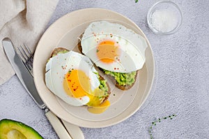 Avocado toast with fried egg and sea salt on a plate on a grey background. A healthy breakfast or lunch. Horizontal orientation