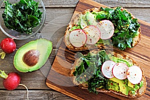 Avocado toast with kale and radish over rustic wood