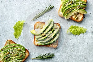 avocado toasts with sesame seeds and pumpkin seeds on on a gray background.