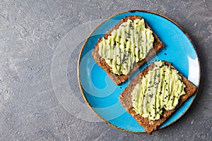 Avocado toasts on whole grain bread, mashed avocado with sesame seeds, healthy eating concept, top view