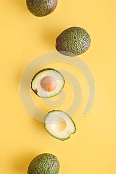 avocado whole and half on yellow background