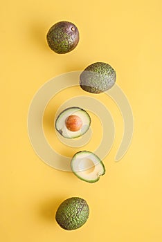 avocado whole and half on yellow background