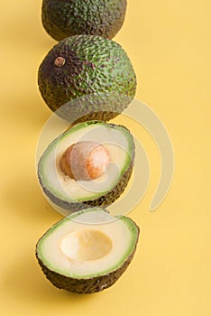 avocado whole and half on yellow background