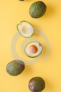 avocado whole and half on yellow background