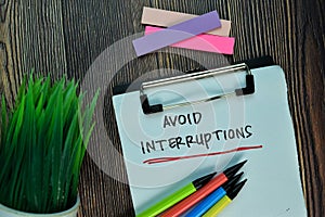 Avoid Interruptions write on a paperwork isolated on Wooden Table. Motivation or Insipiration Concept