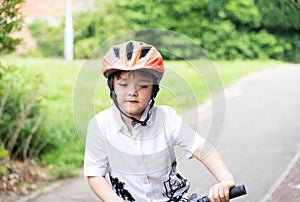 Avtive kid wearing a bike helmet, Outdoors portrait Happy kid with smiling face wearing a cycling helmet riding a bicycle in the