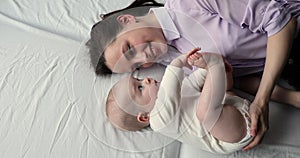 Awaken baby lying on bed near mother, above closeup view