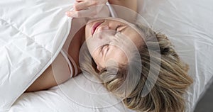 Awakened shocked young woman looks under covers