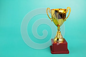 Award cup, gold prize for first place, sports trophy on a green background,copy space