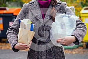 Aware woman separating paper from other waste, putting it into green container to save natural resources in Prague Chezh