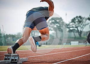 And away he goes. Rearview shot of an unrecognizable young male athlete running on an outdoor track.