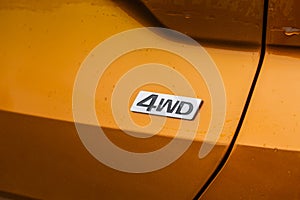 AWD emblem on modern orange SUV car detail close up view.