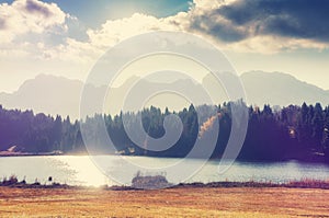 Awesome autumn landscape at mountains valley with lake and sky. View over Geroldsee with wooden hut and Karwendel mountains at