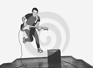 Awesome crazy fashion young musician rock guitar player jumps with passion in studio. Stylish rocky emotional man. Black