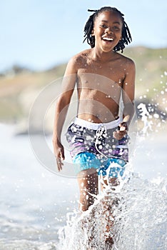 Awesome. An excited young boy charging through the shallows of the sea.