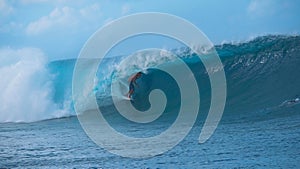 Awesome young surfer rides a beautiful emerald barrel wave in sunny Tahiti.