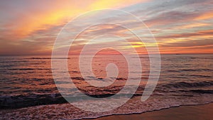 Awesome golden hour sunset at the beach with wonderful pastel colored sky and the waves crashed on the shore