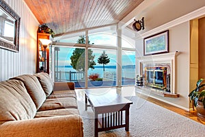 Awesome living room interior with sloped wooden ceiling and water view.