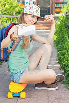 Awesome skateboarder girl making selfie on mobile phone